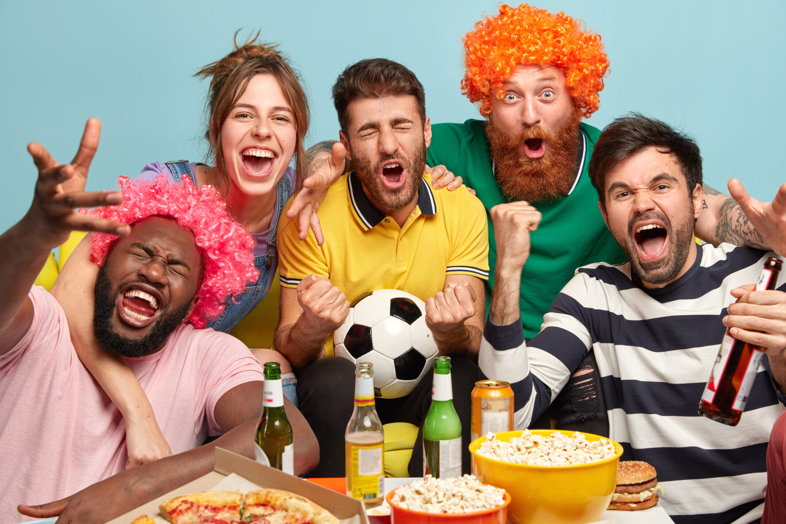 men woman fans watch football tv home enjoy exciting game clench fists celebrate victory express positive emotions have popcorn bowls eat pizza pose blue wall scaled